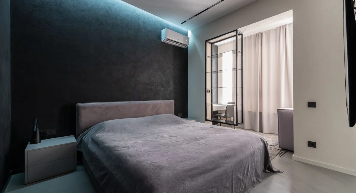 Interior design of contemporary spacious bedroom with comfortable soft bed with bedside table and air conditioner in apartmen