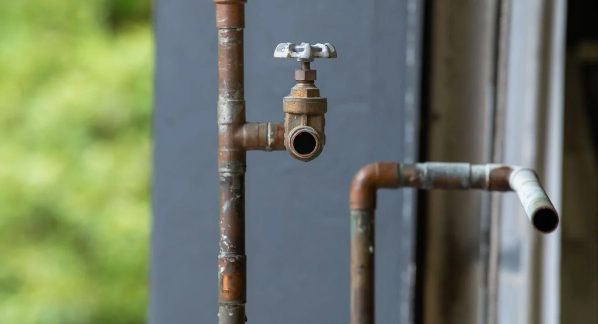 Detailed view of an old, rusty industrial water pipe with valve, conveying vintage industrial aesthetics.