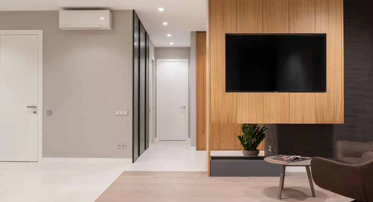 Apartment interior with armchairs and table next to TV on wall and door