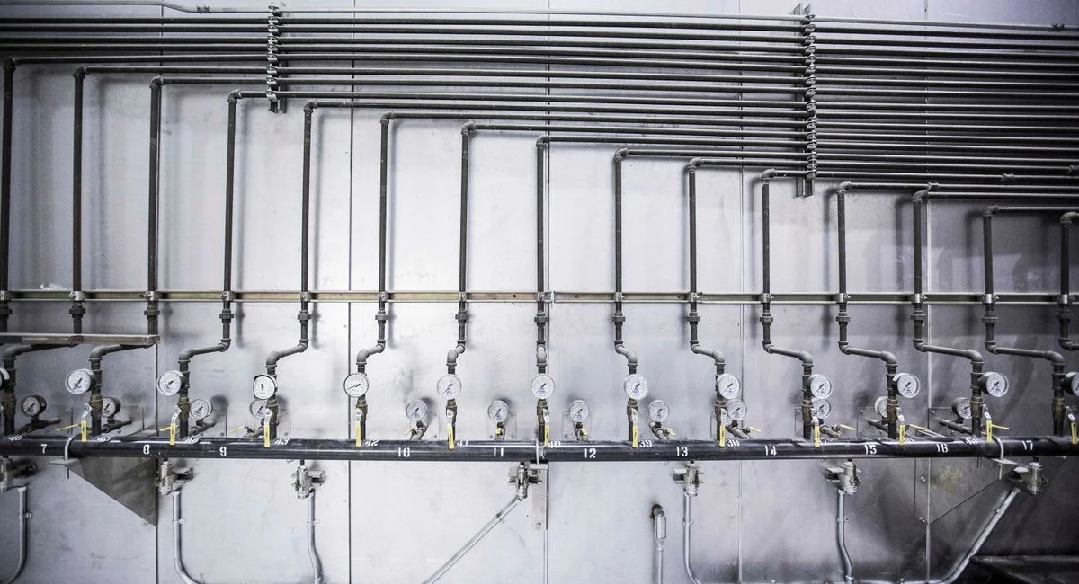 Detailed view of an industrial plumbing system featuring multiple pressure gauges and steel pipes.