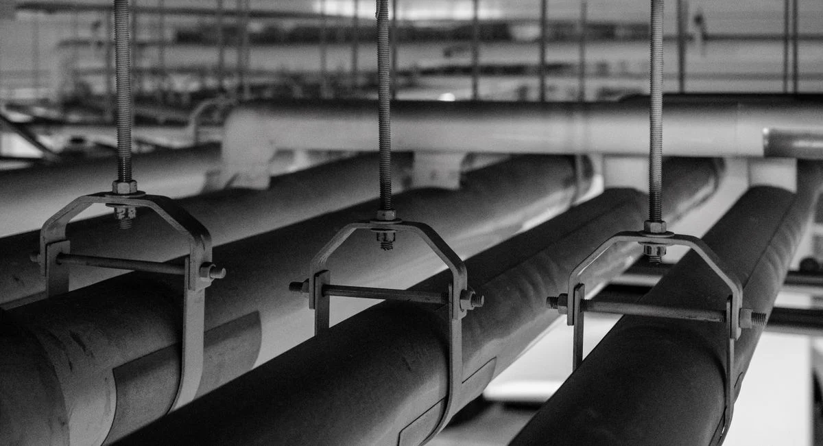 Black and white photo of industrial pipes and fittings, captured in a production facility.