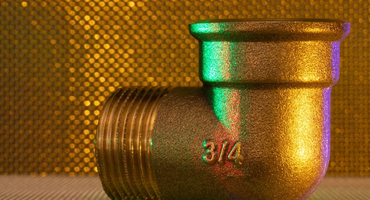 A golden 3/4 inch pipe fitting against an elegant, textured, golden backdrop.