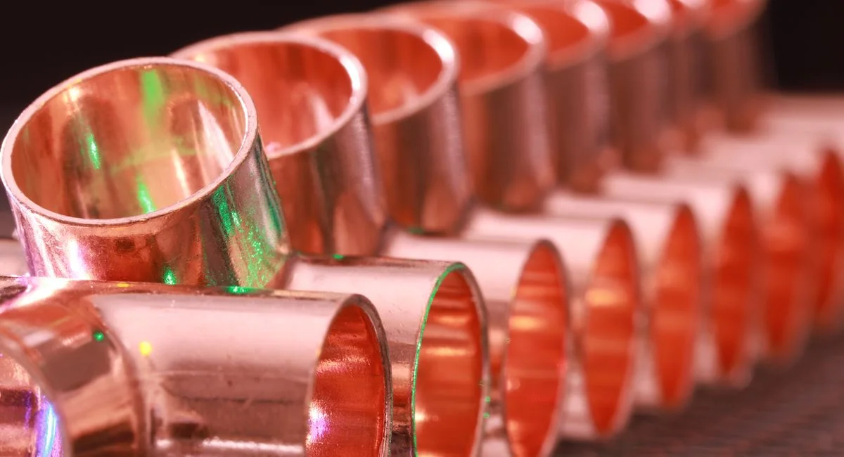 Copper plumbing fittings arranged in a row, showcasing metallic texture and industrial detail.
