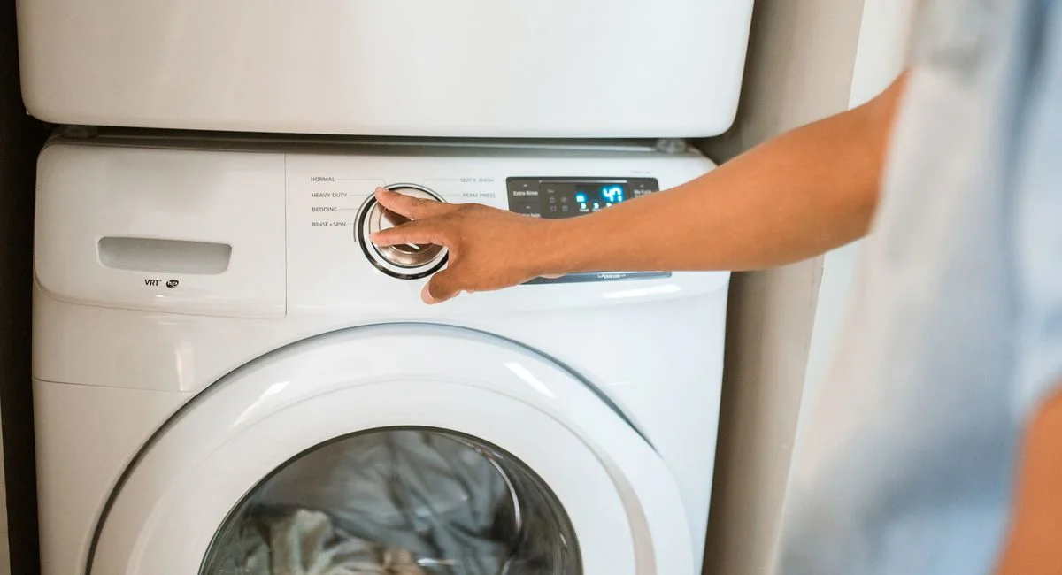 Close-up of a person adjusting a washing machine in a modern laundry room.