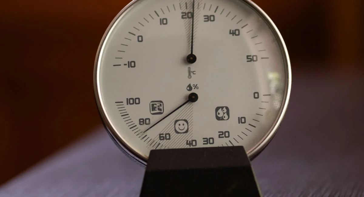 Close-up of an analog hygrometer and thermometer displaying temperature and humidity indoors.